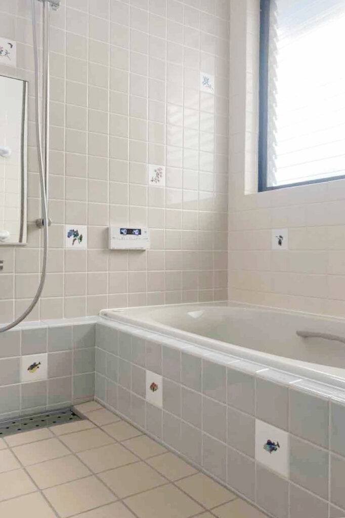 タイル工法の浴室を、一から造り替えるリフォーム工事。<br />
<br />
浴槽はLIXILのデザイン浴槽『シャイントーン浴槽』で施工しました。洗練されたフォルムと上質さ、重厚感のある人造大理石の浴槽です。保温浴槽サーモバスSがついており、浴槽の保温材で寒い在来浴室でもお湯が冷めにくく、温かさ長持ち！<br />
<br />
浴槽内部には大型グリップが取付られており、浴槽への出入りも安心です。<br />
<br />
浴室上部には、「プッシュワンウェイ式排水栓」がついており、ムリに腰をかがめることなく、ボタンひとつで貯排水ができます。<br />
<br />
水まわり抗菌の床タイルを使用し、その他部材も調湿をしてくれる材料を取り入れ、防水面も安心です。<br />
<br />
浴槽・壁面のタイルには、デザイン性のあるものをポイントで取付、風情もありつつセンスの光る浴槽に生まれ変わりました。