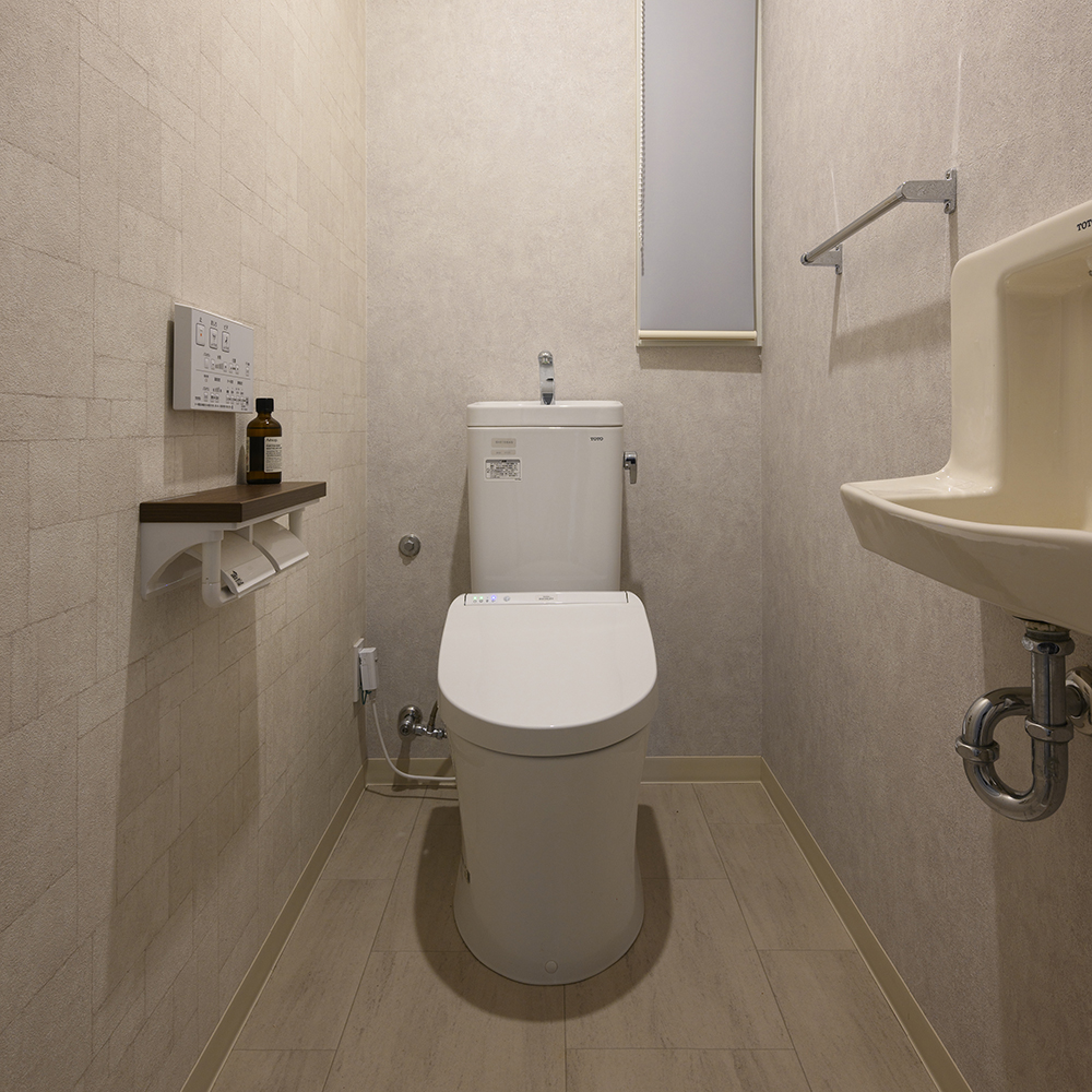 トイレ設備は既存を利用し、明るく上品な壁紙と床材へ一新したトイレ空間。
