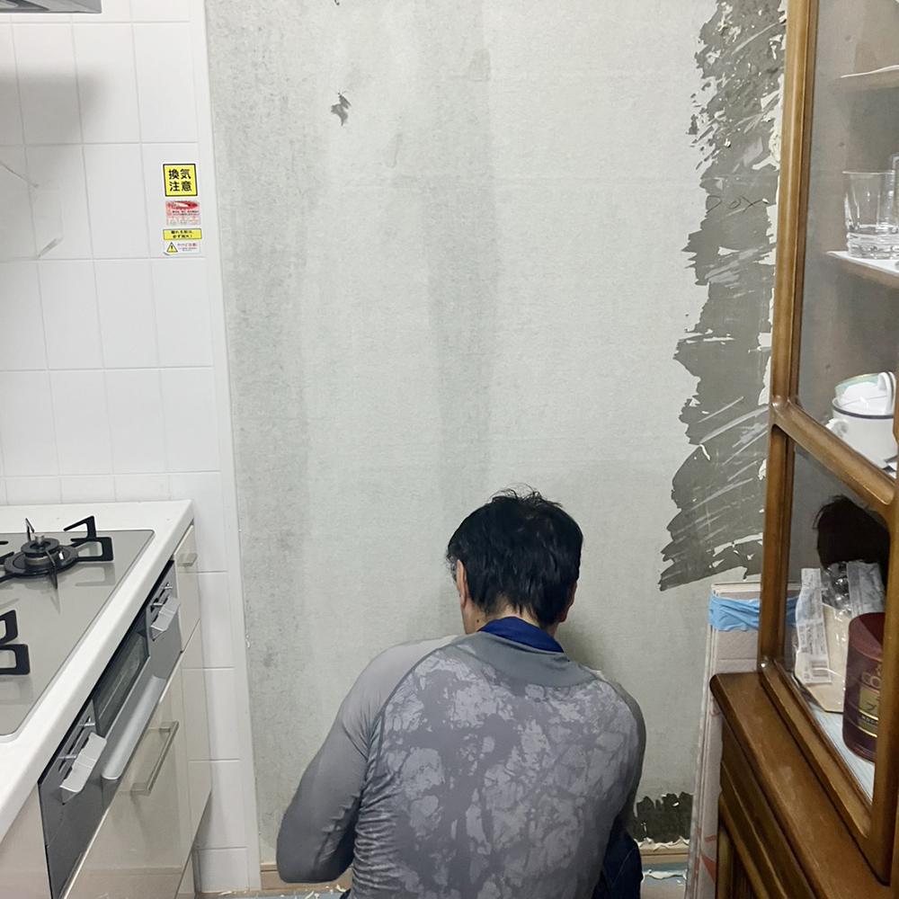 壁面のクロスを剥がし、キッチンパネルが重みで落ちてこないよう下地処理を施して施工を進めます。