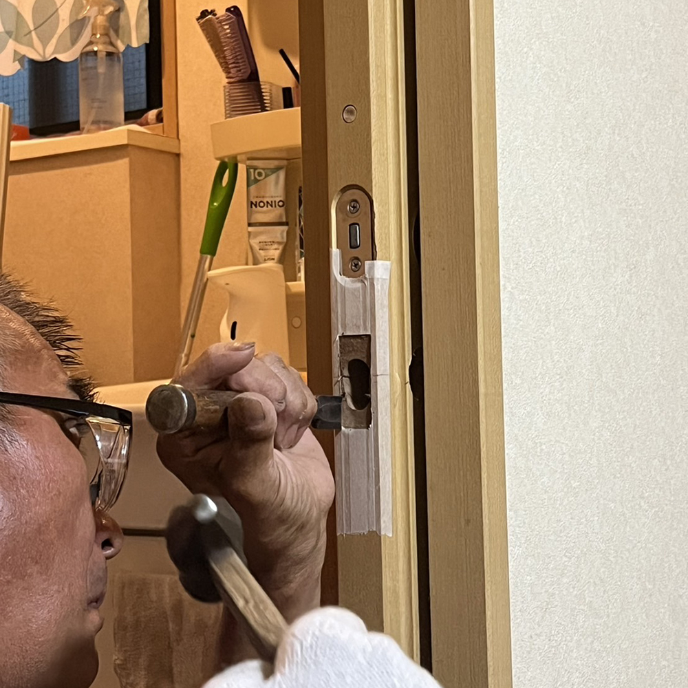 職人さんが、サムターン（鍵の一部）をつける部分をノミでほっています。