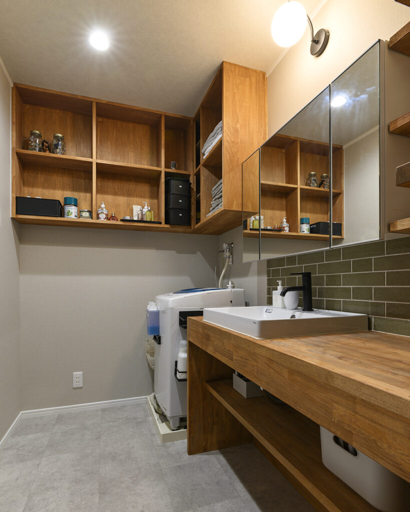 洗面所には造作棚を設置し見せる収納を意識。<br />
オリーブ色のタイルがアクセントに。