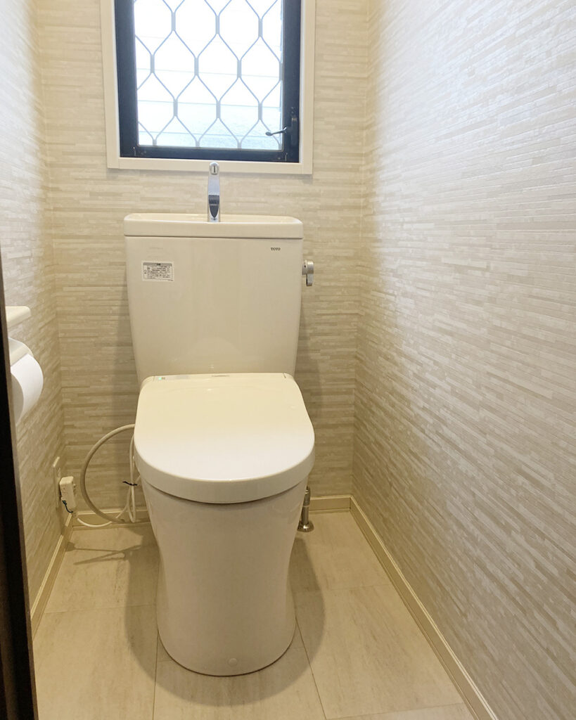壁紙はホワイトからベージュのグラデーションの石目調の柄をセレクト。<br />
温かみと清潔感のあるトイレ空間が完成しました。