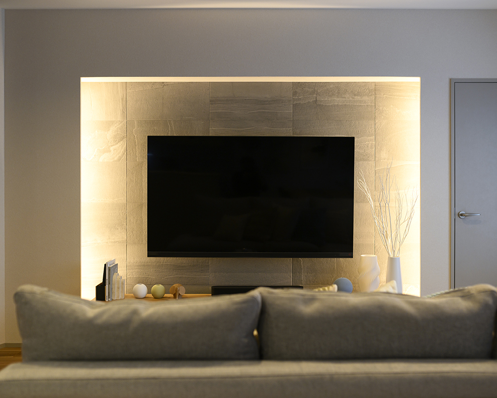 リビングのテレビ背面にはエコカラットを施工。
デザイン性はもちろん、調湿・消臭といった機能性にも優れたタイルです。
間接照明に照らされたエコカラットが、空間にラグジュアリーな雰囲気を添えています。