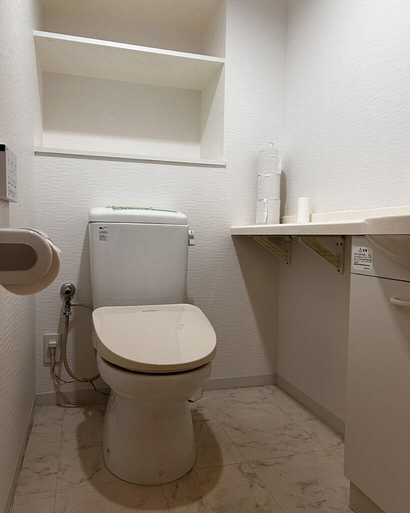 以前はホワイトを基調とした、タンク付きの標準的なトイレでした。
背面の棚などは実用的ではありましたが、全体的に古さが感じられ、細かな凹凸が多くお掃除が大変な状態でした。