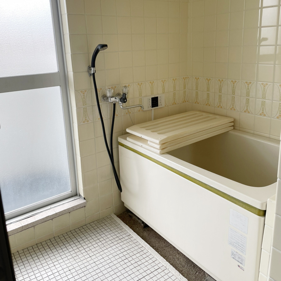 タイル張りの壁や床に加えてベランダへ繋がるドアもあり、断熱性能が低いリフォーム前の浴室。
