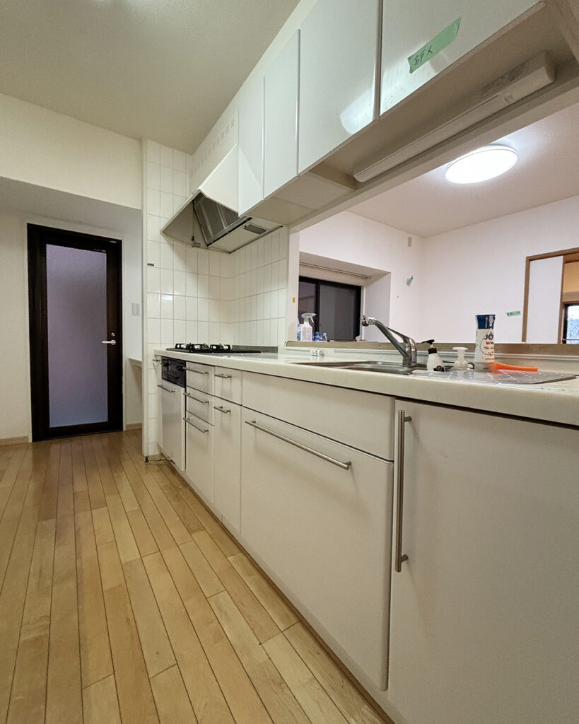 以前は白を基調とした標準的なキッチンでしたが、上部の吊り戸棚があることでリビングとの間に閉塞感がありました。
また、この吊り戸棚が壁となり、リビングからのエアコンの風がキッチン内まで届きにくいという機能面の課題もありました 。