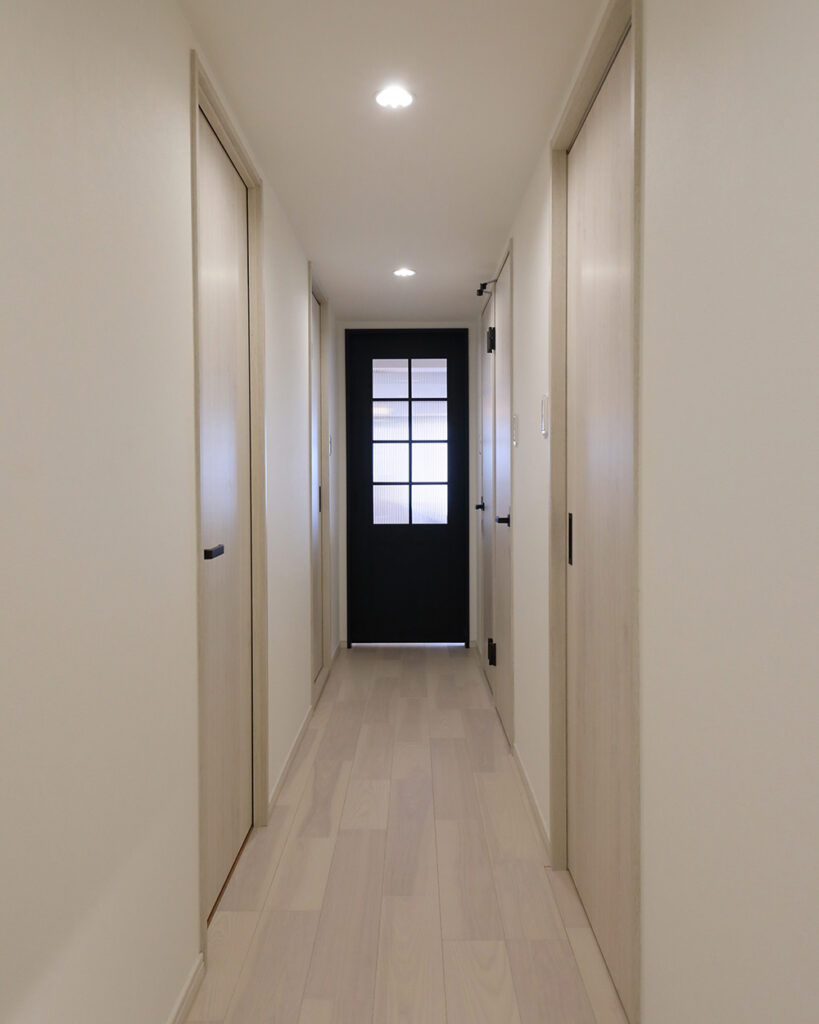 廊下側から見ると、個室のドアはすべてホワイトで統一しました。<br />
写真中央の濃紺の扉の先はリビングです。