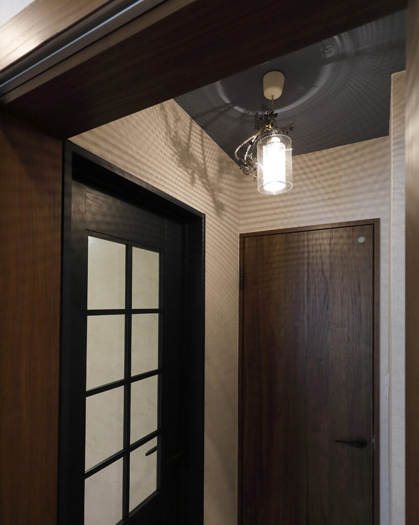 トイレ前の造作洗面スペースは、天井の壁紙と扉色を濃紺でコーディネート。<br />
照明の印影が美しいノスタルジックな空間となりました。